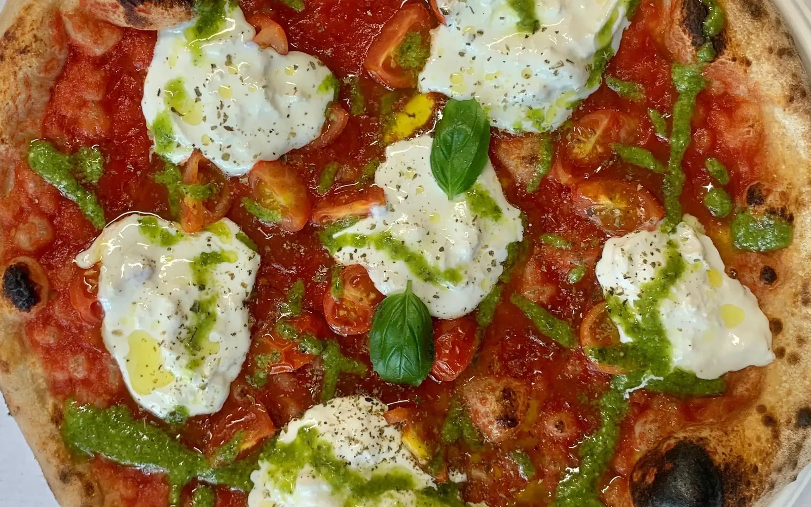 Pizza Mystic appena sfornata, con pomodorini, stracciatella, basilico e pesto