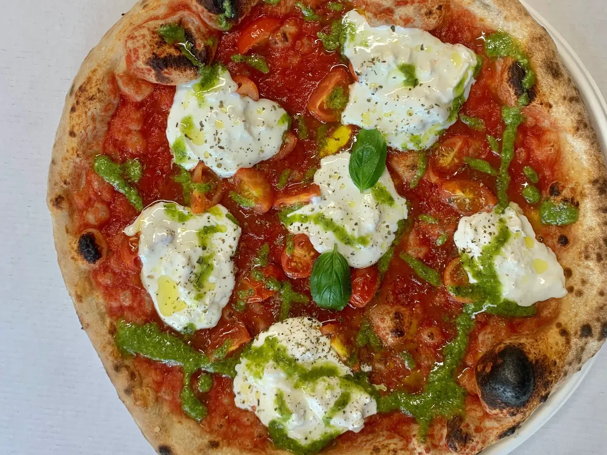 Pizza intera con pomodorini, stracciatella e pesto, vista dall’alto